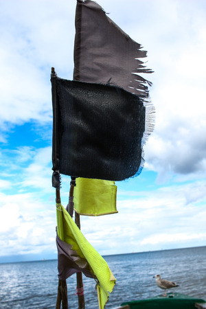 Colorful red blue and black flags on a boat or ship against blue sky with clouds at Baltic Sea in Polandの写真素材