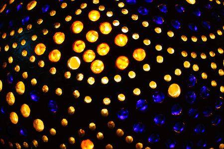 Detail of Indian lamp with lots of colorful yellow red and blue dots with light in the dark