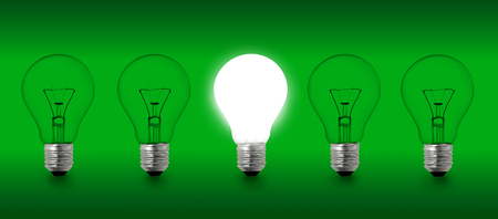 Row of a 5 light bulbs photograph on a green background isolatedの写真素材