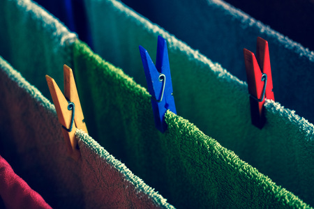 Colorful faded retro vintage background of lines of towels hanging with colorful clips , dark nostalgic moodの写真素材