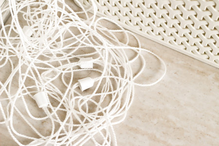 Close up detail of white laundry rope in bathroom lying on marble floor.