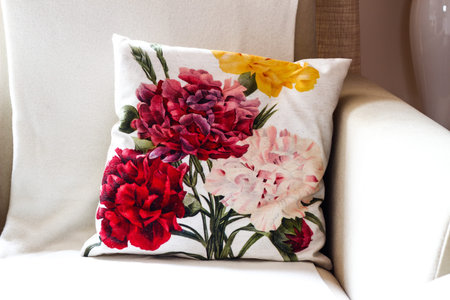 Pillow in flowers pattern on a cozy white chairの写真素材