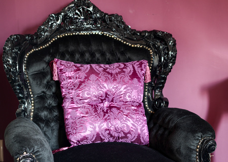 Classic luxurious royal black armchair richly decorated with ornaments carved in wood. Purple cushion pillow.の写真素材