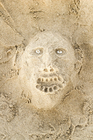 Scary face with teeth and eyes made of shells made of sand on beachの写真素材