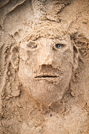 Sand face of an old tired man made on beachの写真素材