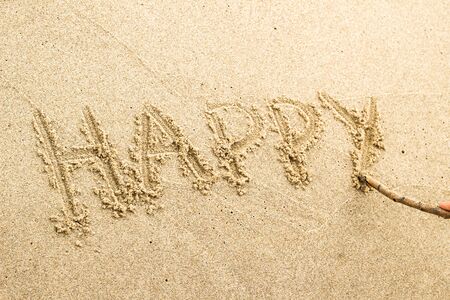 Nice, pleasant and simple sunny summer composition on holidays. Happy relaxing vacations. Text words on wet sand on beach, concept of being happyの写真素材