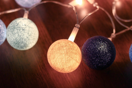 Decorative glowing in the dark black cotton ball lights background. Many balls of shades of blue,...