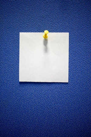 White stickers attached to blue board with colorful pins at the officeの写真素材
