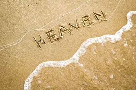 Nice, pleasant and simple sunny summer composition on holidays. Happy relaxing vacations. Text words on wet sand on beach: Heavenの写真素材