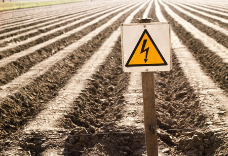 Plowed field, rows on brown ground. Very nice back sun light. No entry, sign of danger electric...