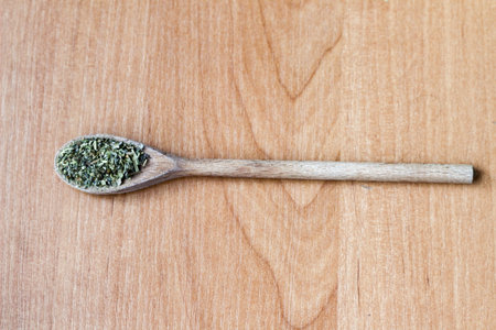 Composition of a wooden spoon with green spices and small black pepper ballsの写真素材