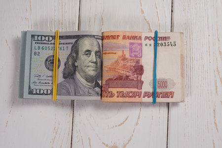 Closeup of a hundred-dollar bills and five thousand rubles on a light background