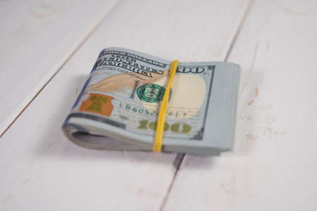 Close-up of a stack of hundred-dollar bills on a light background