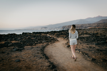 Girl walks through the desert not far from the ocean in the evening. Tenerifeの写真素材