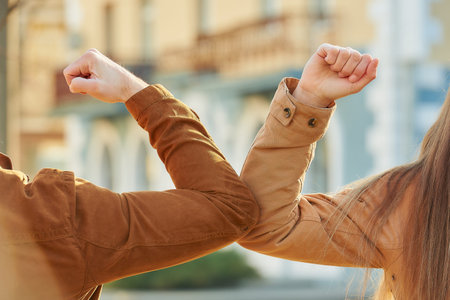 Elbow greeting to avoid the spread of coronavirus (COVID-19). Man and woman meet on the street with...