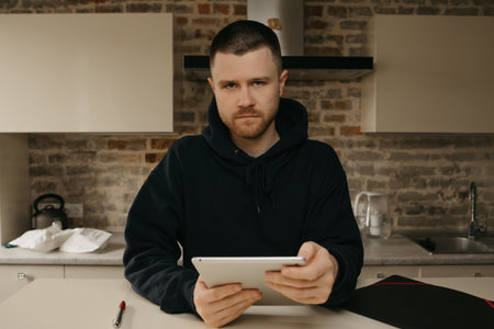 Remote work. A man with a beard working remotely on his tablet. A fellow doing business at home.
