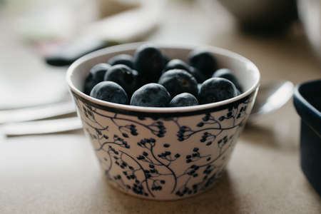 A cup of blueberries is on the table in the kitchen.の写真素材