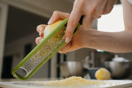 A close dynamic photo from below of the hands of a woman who is separating the lemon zest with a...