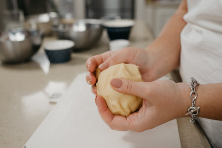 A close photo of the hands of a woman who is holding shortbread dough in the kitchen