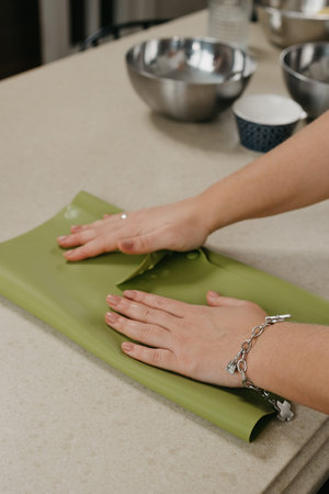 A close photo of the hands of a young woman who is stacking out shortbread dough in the kitchen