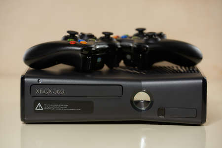 Minsk, Belarus - FEBRUARY 03, 2021: A close-up front view of the used lying XBOX 360 Slim (Corona) 250GB Console and two gamepads and on it.のeditorial素材