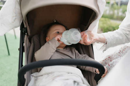 An infant baby in the stroller is drinking from her bottleの写真素材