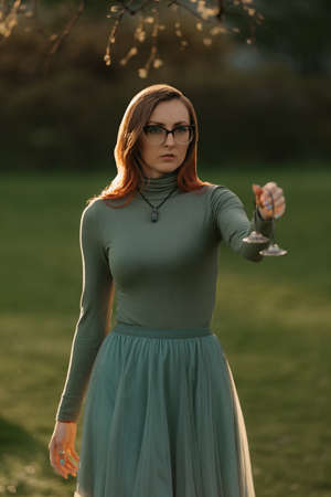 A female redhead magician holds Reiki Tibetan Cymbals for chimes sound therapy. Session of a meditation healing in the park at sunset.の写真素材