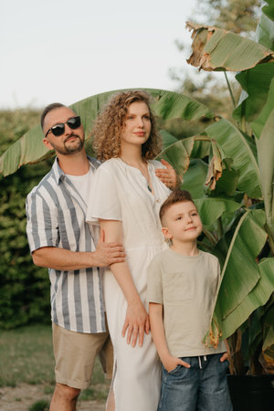 Father, mother, and son are having fun with palm trees in the background.の写真素材