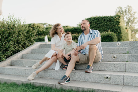 Father, mother, and son are sitting on the steps in the garden of an old townの写真素材