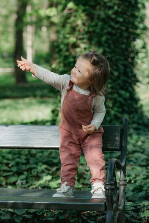 A female toddler is on the garden bench in the park.の写真素材