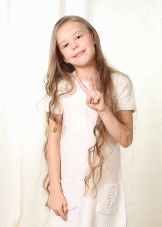 Little beautyful blond girl shows sign victory and smileの写真素材