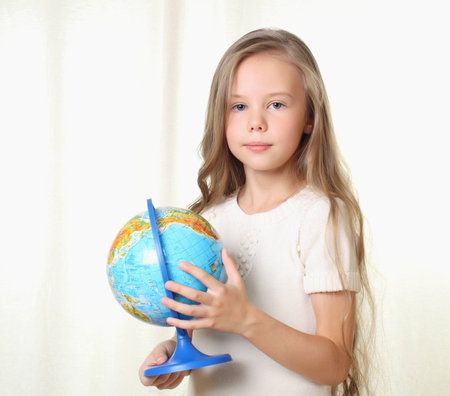 Little blond girl holding globe and looking on cameraの写真素材
