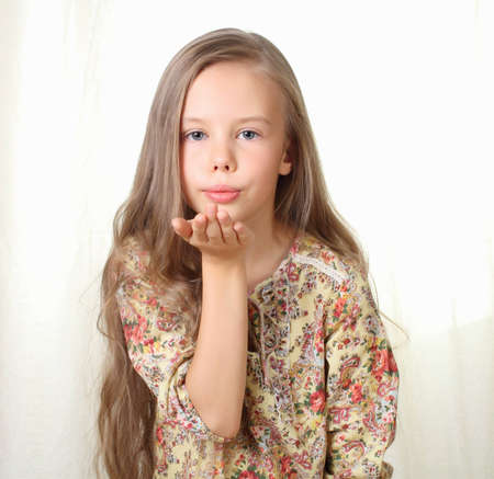 Little blond girl sends air kiss and blowingの写真素材