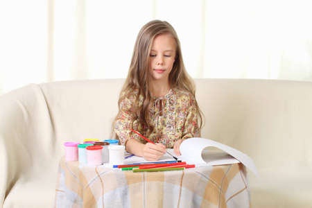 Little blond girl drawing at home on sofaの写真素材