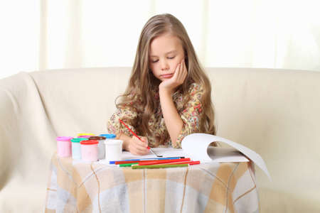 Little blond girl drawing at home on sofaの写真素材