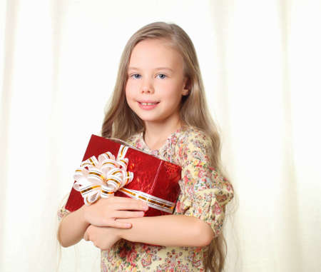 Little blond girl holding a red glamorous giftの写真素材