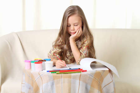 Little blond girl drawing at home on sofaの写真素材