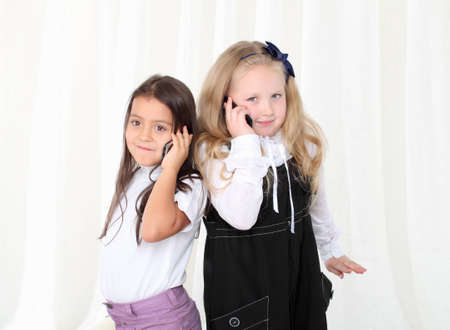 Two little girls calling by phone to each otherの写真素材