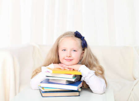 Little girl reading a book sitting on sofa