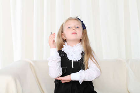 Little girl rised hand near books sitting on sofaの写真素材