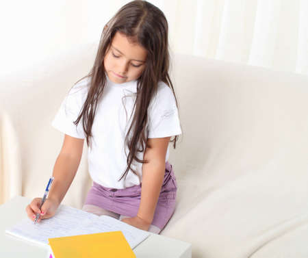Little girl reading a book sitting on sofaの写真素材