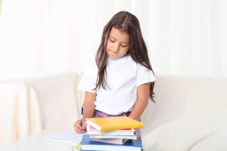 Little girl reading a book sitting on sofaの写真素材