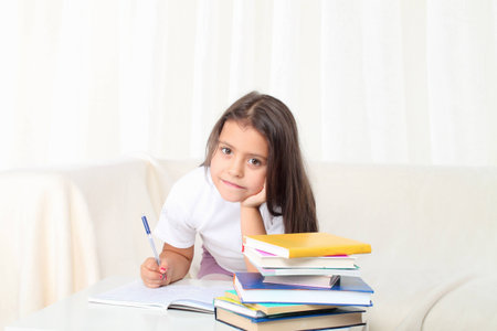 Little girl reading a book sitting on sofa