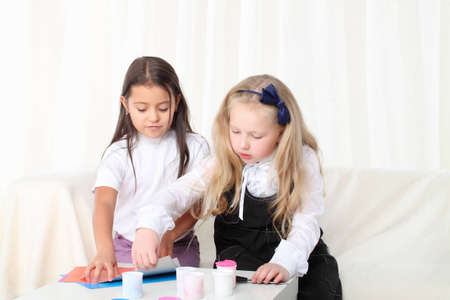 Two little girls sculpting clay on sofa in roomの写真素材