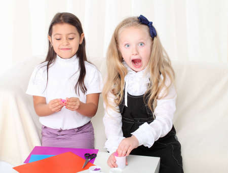 Two little girls sculpting clay on sofa in roomの写真素材