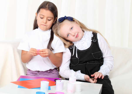 Two little girls sculpting clay on sofa in roomの写真素材