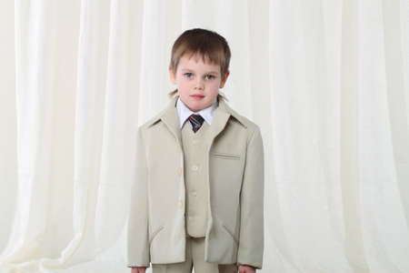 Portrait of smart little blond boy in suit at homeの写真素材