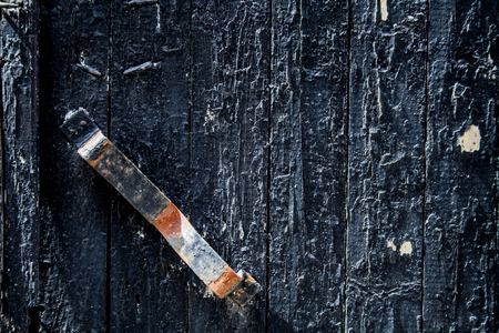 Old faded black garage door with rusty handle. Background, vintage.の写真素材
