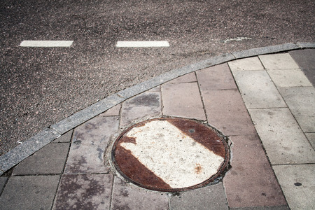 Rusty sewer hatch with white marking near the road. Urban, background.の写真素材