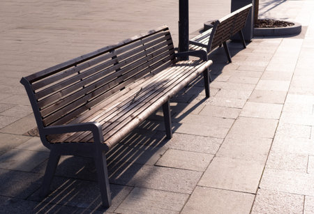 brown wooden bench on the street at sunset. furniture, city.